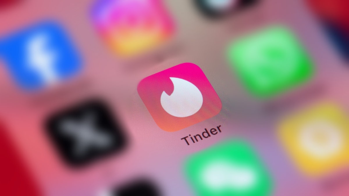 A smartphone screen showing the Tinder app clearly surrounded by other blurred apps