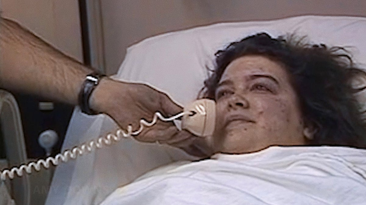 Amy Downs laying in bed talking on the telephone.