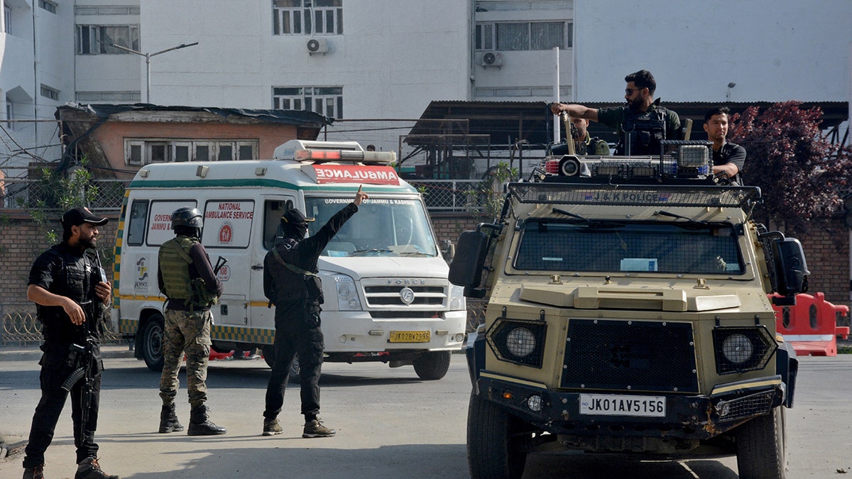 Indian security forces personnel escort an ambulance carrying the bodies of tourists who were killed in a suspected militant attack near Pahalgam, outside the police control room in Srinagar