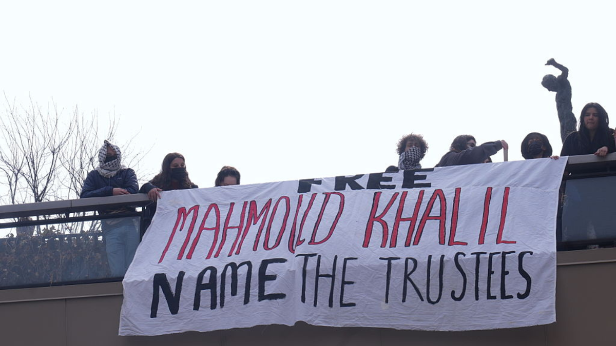 Protesters display a large banner reading "Free Mahmoud Khalil, Name the Trustees" from a balcony as students chain themselves to the gates of Columbia University, demanding accountability from the university's trustees following the arrest of Mahmoud Khalil, in New York, on April 2, 2025.