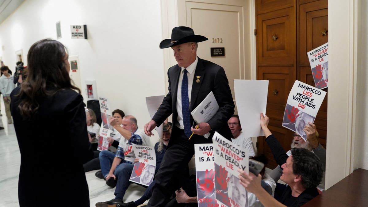 U.S. Representative Ryan Zinke (R-MT) walks past protesters as Pete Marocco, deputy administrator-designate at the U.S. Agency for International Development (USAID), attends a meeting with members of Congress to discuss foreign assistance, on Capitol Hill in Washington, D.C., U.S. March 5, 202