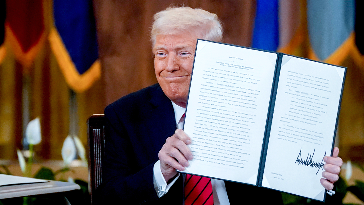 Trump holding executive order, smiling