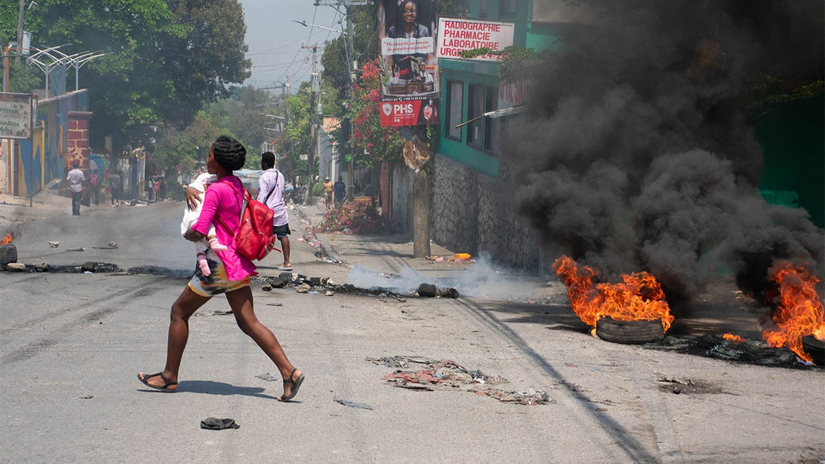 A woman carrying a child runs after gunshots were heard in Port-au-Prince, Haiti