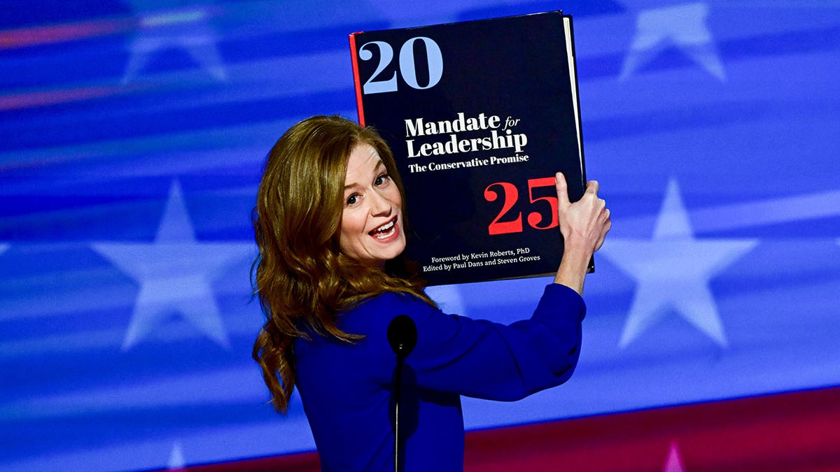 Mallory McMorrow holds up Project 2025 on stage