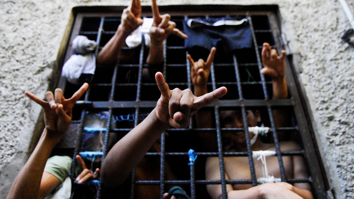People arrested this week for being members of the MS-13 Mara Salvatrucha street gang among other crimes, flash their gang's hand sign from inside a jail cell at a police station in San Salvador October 12, 2012. The U.S. on Thursday imposed financial penalties on violent Latin American street gang MS-13, which has thousands of members operating in the U.S. and has been accused of human trafficking, kidnapping, murder, rape and other criminal activities. MS-13, whose U.S. members are mostly first-generation Salvadorean-Americans or Salvadorean nationals, was added to the Obama administration's list of transnational criminal organizations - a label designed to cripple a criminal group's finances. REUTERS/Ulises Rodriguez (El SALVADOR - Tags: CIVIL UNREST CRIME LAW) - GM1E8AD0V8101