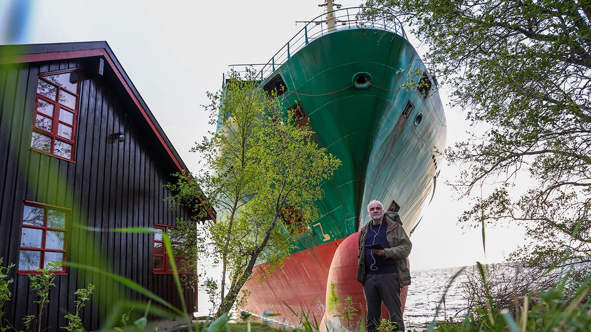 Johan Helberg stands next to his house and NCL container ship ran aground
