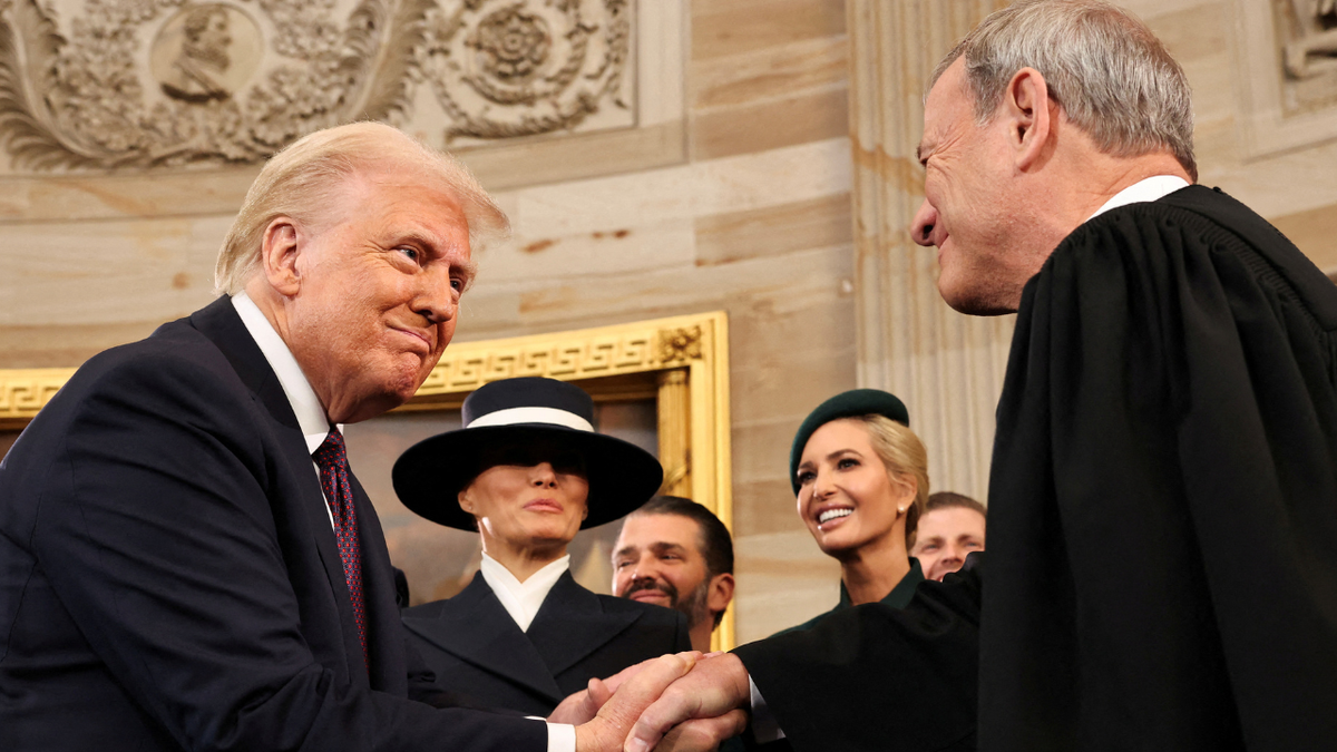 President Donald Trump shakes hands with Supreme Court Chief Justice John Roberts as Melania Trump, Donald Trump Jr. and Ivanka Trump look on after being sworn in during inauguration ceremonies