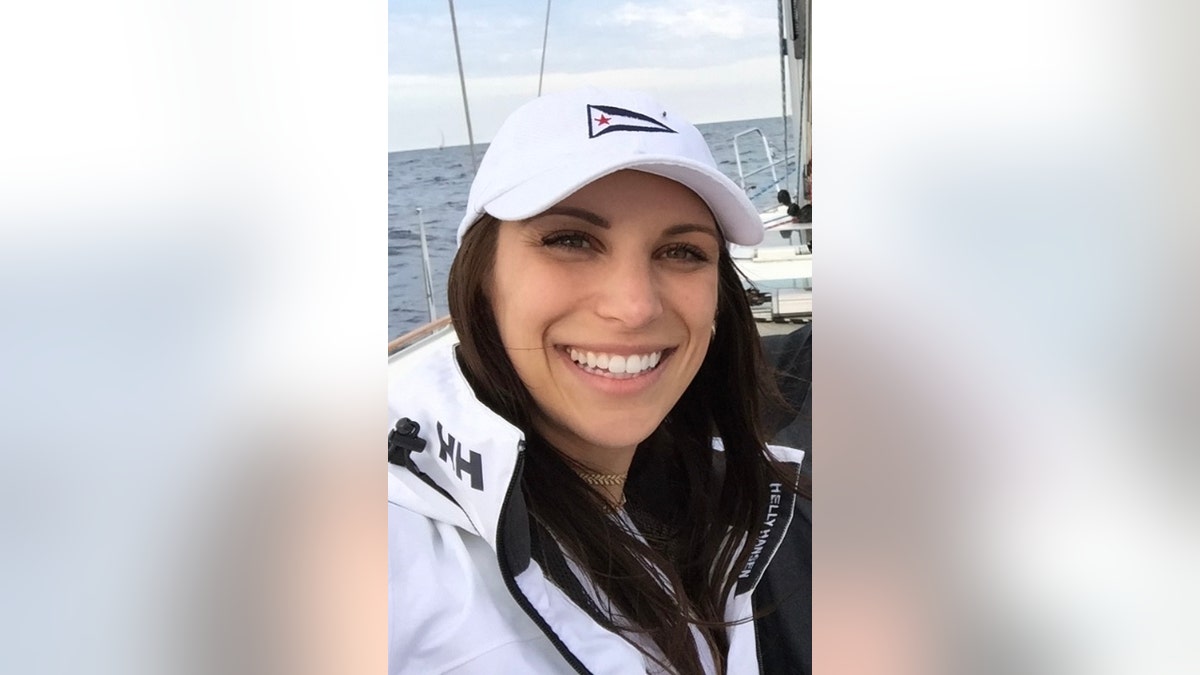 Caitlin Tracey wearing a white baseball cap and jacket on a sailboat