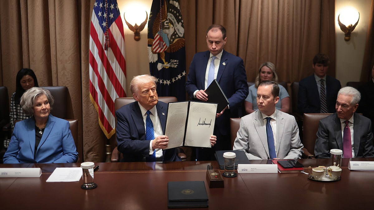 U.S. President Donald Trump holds an executive order he signed during an Ambassador Meeting in the Cabinet Room of the White House with (left to right) Chief of Staff Susie Wiles; Sergio Gor, assistant to President Donald Trump and director of the Presidential Personnel Office; and Charles Kushner, nominee for U.S. Ambassador to France, on March 25, 2025, in Washington, D.C.