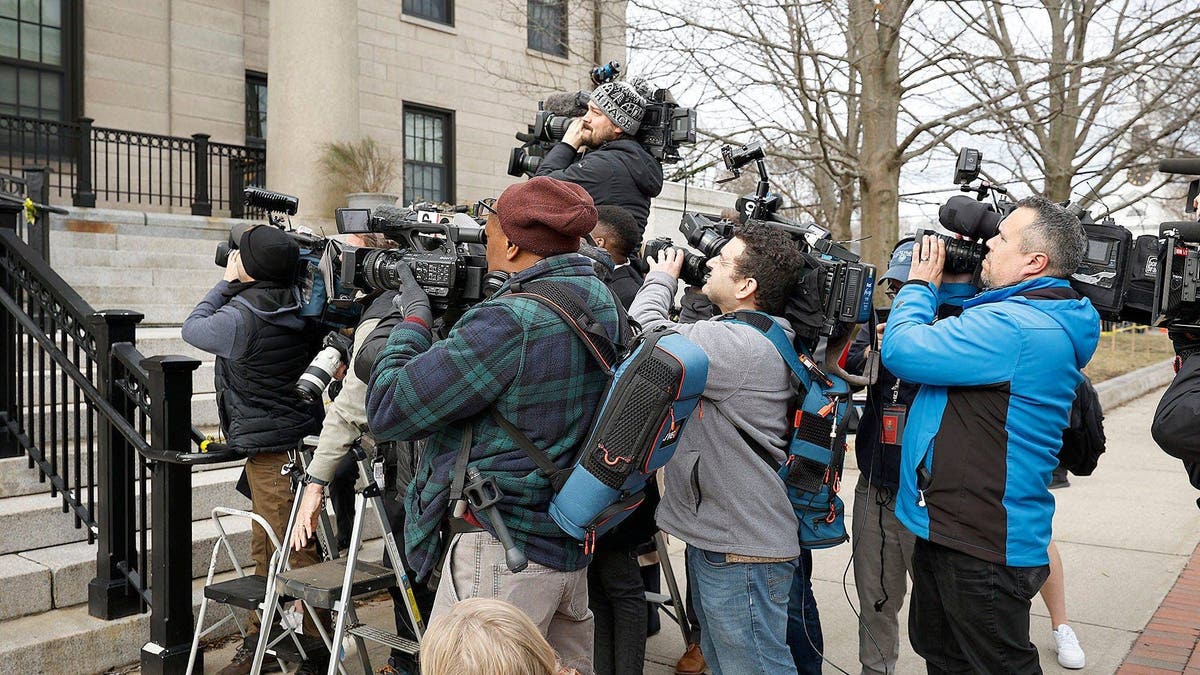 A group of news photographers aim their cameras up the courthouse steps in Dedham, Massachusetts
