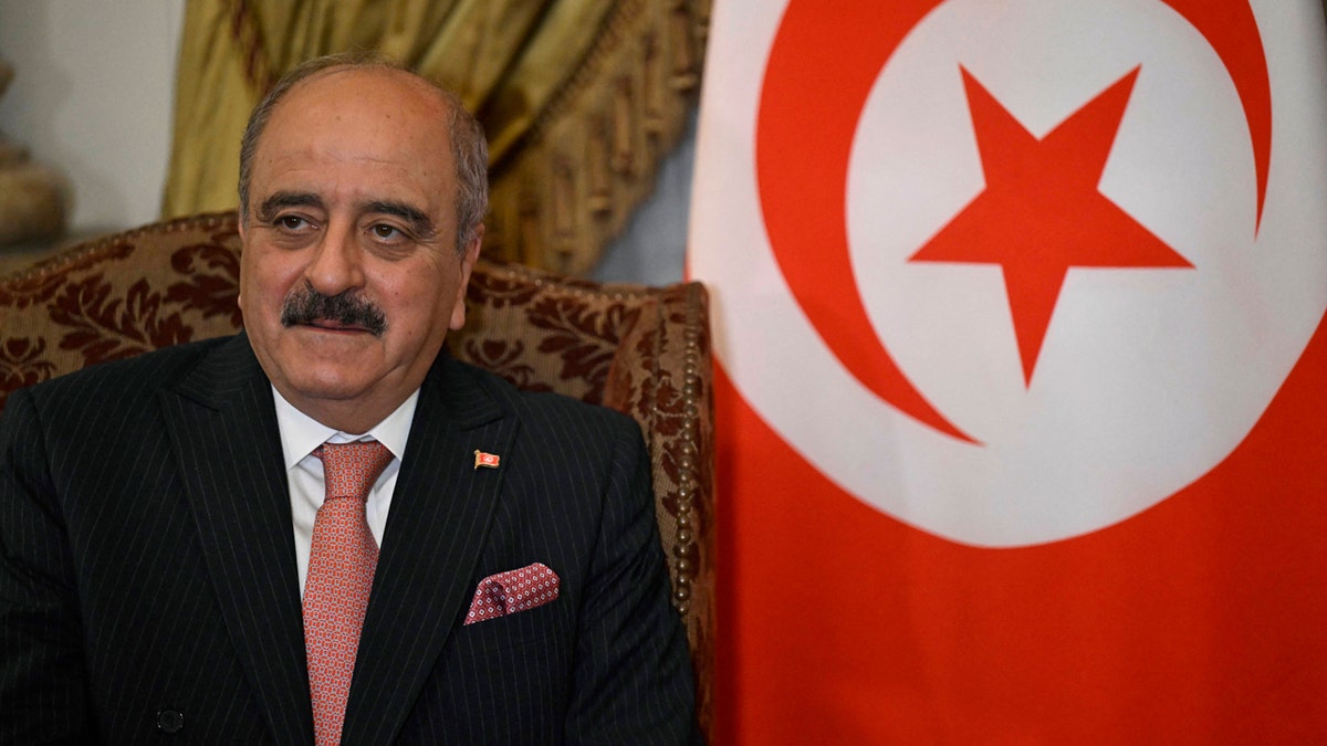 Mohamed Ali Nafti next to a Tunisian flag