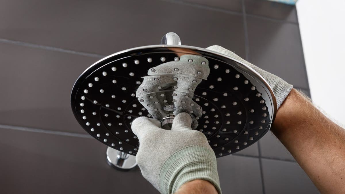 Worker's hands install the head of the built-in shower faucet.