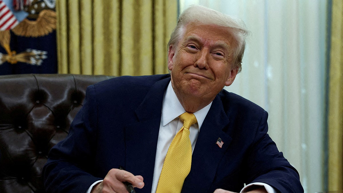 Donald Trump at Oval Office desk, smiling, closeup shot