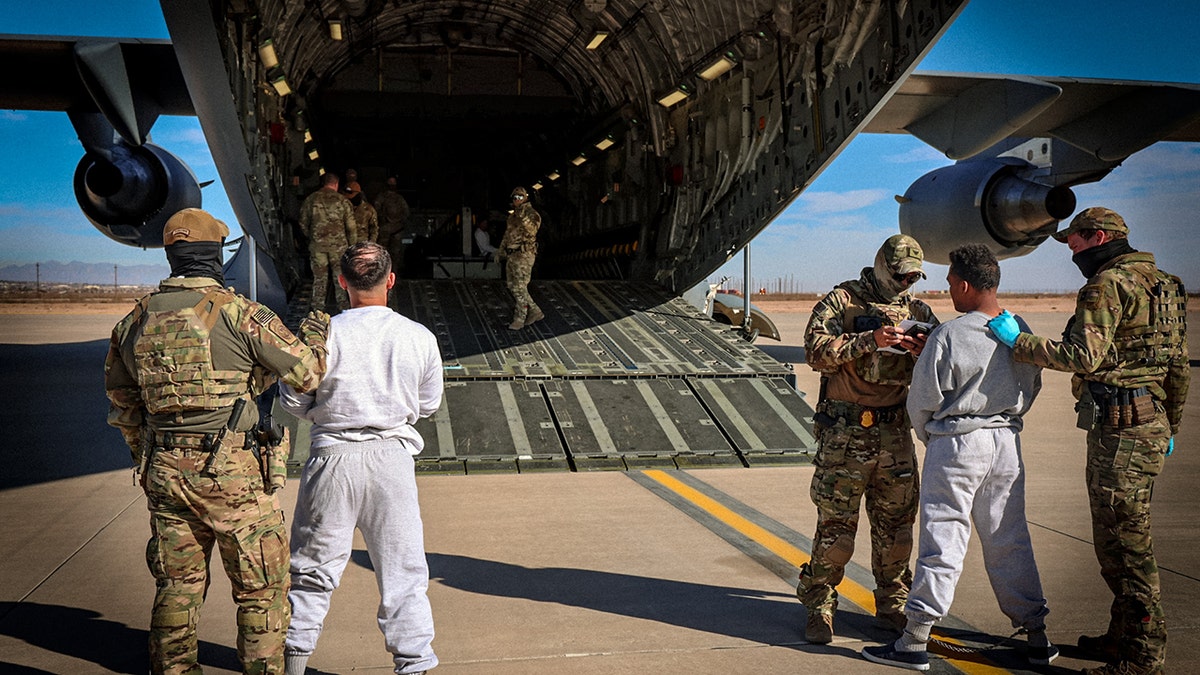 deportees being escorted onto military plane