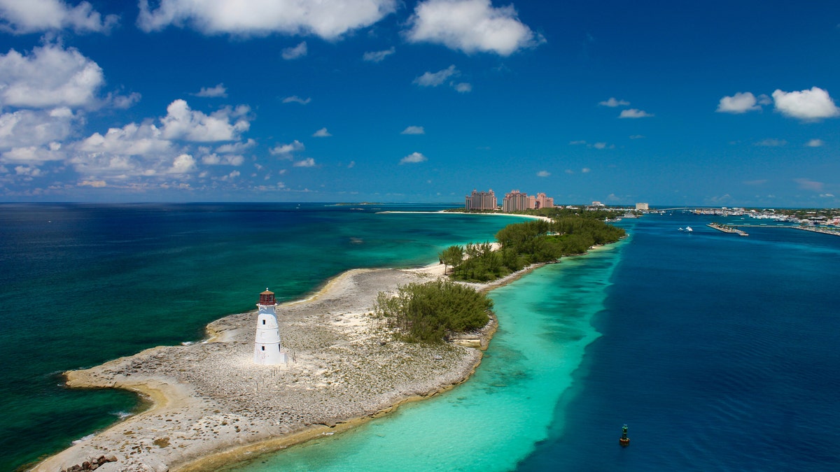 Lighthouse guarding the port to Nassau, Bahamas. Bright blue, crystal clear ocean water with blue sky