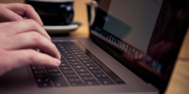 Detail of someone typing on the keyboard of an Apple MacBook Pro laptop computer in a cafe, taken on November 18, 2016. 
