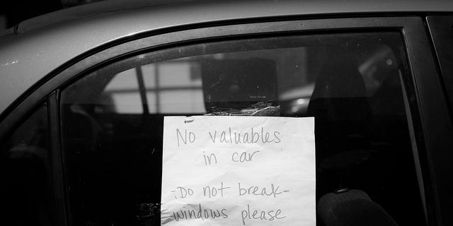 A sign in a parked car in San Francisco asks for the windows not to be broken and informs that there are no valuables inside.