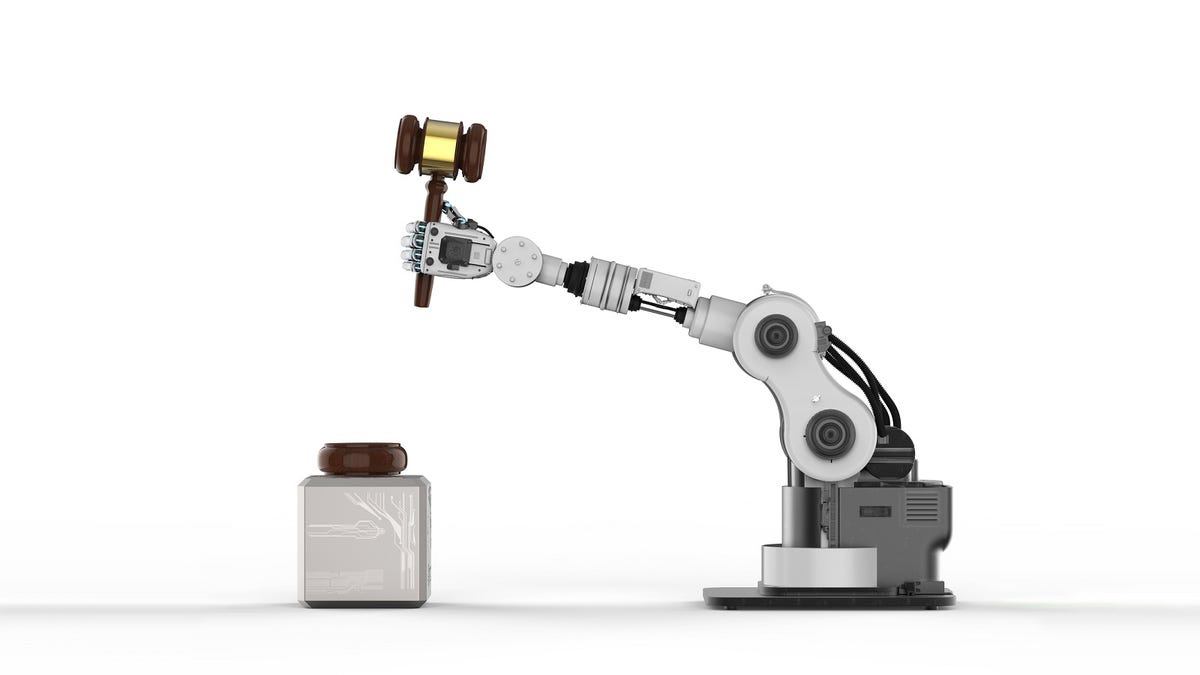 A robot arm holds a gavel poised in the air, ready to slam it down.
