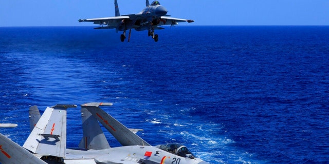 In this photo released Dec. 31, 2021, by Xinhua News Agency, an undated photo shows a carrier-based J-15 fighter jet preparing to land on the Chinese navy's Liaoning aircraft-carrier during open-sea combat training.  