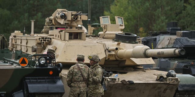 British soldiers chat next to U.S. Abrams tanks during joint military exercises in Nowa Deba, Poland, on Sept. 21, 2022. (Artur Widak/Anadolu Agency via Getty Images)