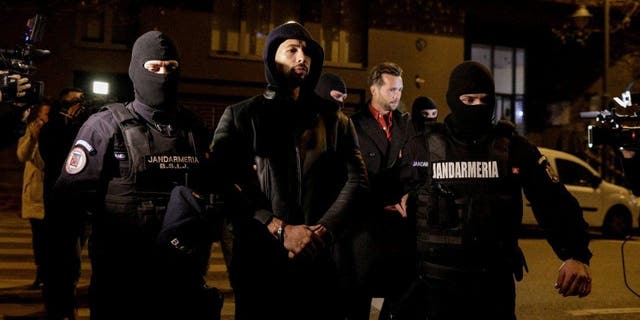 Andrew Tate and Tristan Tate are escorted by police officers outside the headquarters of the Directorate for Investigating Organized Crime and Terrorism in Bucharest (DIICOT) after being detained for 24 hours, in Bucharest, Romania, Dec. 29, 2022.