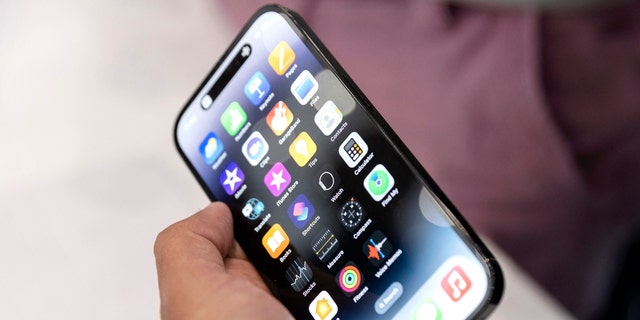 An Apple associate holds one of the new iPhone Pros during a launch event for new products at Apple Park in Cupertino, California, on September 7, 2022.