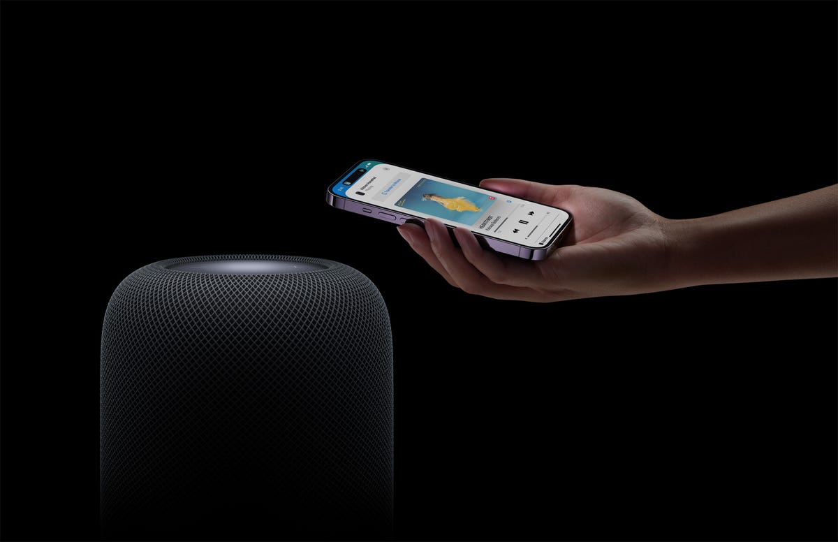 An Apple HomePod speaker next to an iPhone.