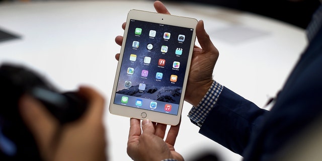 A member of the media displays an Apple Inc. iPad Mini 3 for a photograph after a product announcement in Cupertino, California, U.S., on Thursday, Oct. 16, 2014. 