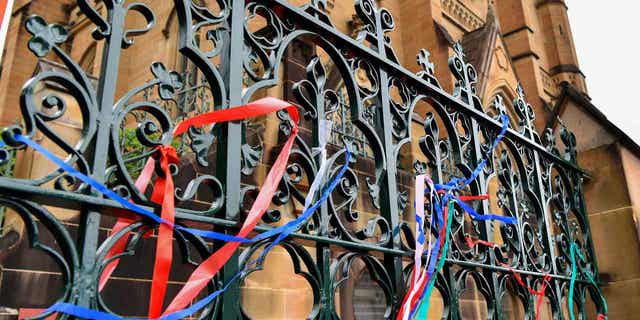 Ribbons are tied onto a fence at a protest at St Mary's Cathedral, in Sydney, on Jan. 31, 2023. Police plan to ask a judge to ban protesters from demonstrating outside St. Mary's Cathedral during Cardinal George Pell's funeral on Thursday.