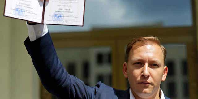 Andrey Dzmitryeu shows his presidential candidate's identification card after he was registered as a candidate for the presidential elections in Minsk, Belarus, on July 14, 2020. Dzmitryeu is facing four years in prison for his involvement in protests following the election.