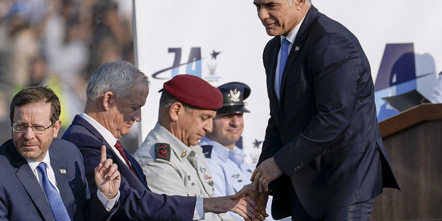 Israeli Prime Minister Yair Lapid, right, shake hands with Israel's Defense Minister Benny Gantz during a graduation ceremony for new Israel's air force pilots in Hatzerim base near the southern Israeli city of Beersheba, on Wednesday, Dec. 28.