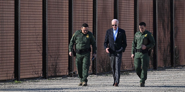 U.S. President Joe Biden speaks with a member of the US Border Patrol as they walk along the U.S.-Mexico border fence in El Paso, Texas, on January 8, 2023. 