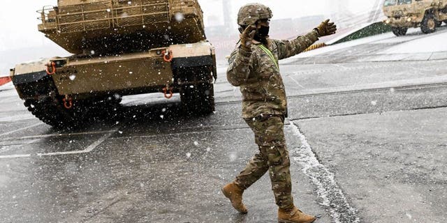 A US Army soldier signals the way to a M1A2 Abrams battle tank that will be used for military exercises by the 2nd Armored Brigade Combat Team, at the Baltic Container Terminal in Gdynia on Dec. 3, 2022. 