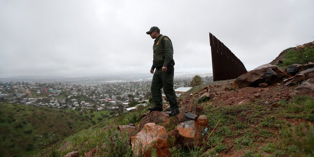 Border Patrol agent Vincent Pirro looks on near where a border wall ends that separates the cities of Tijuana, Mexico, left, and San Diego, in San Diego.