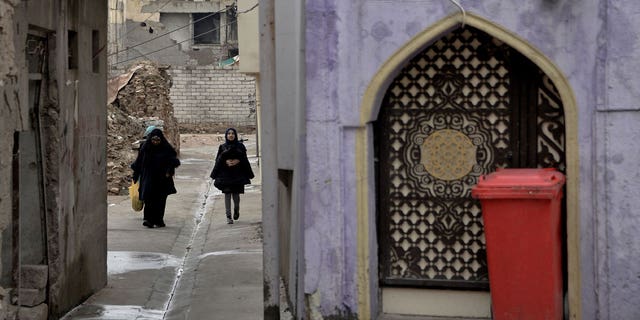 A building under construction collapsed Thursday in Iraq's northern city of Mosul, killing three and injuring nine. Pictured are Iraqi women walking in a partially renovated area in Mosul's war-damaged Old City, on Nov. 30, 2022.