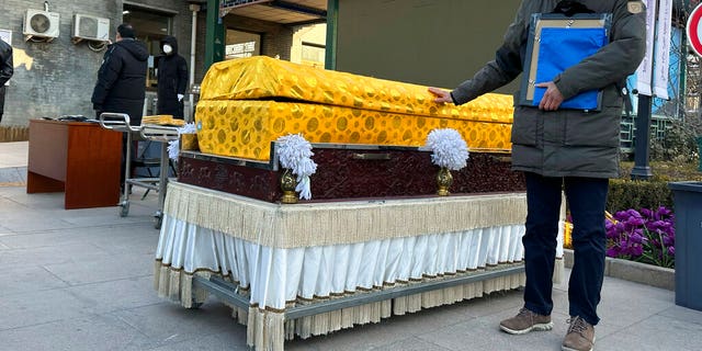 A man places his hand on a casket outside a crematorium in Beijing on Dec. 31, 2022.