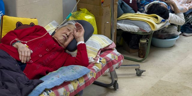 Elderly patients rest along a Beijing hospital corridor as they receive intravenous drips on Jan. 5, 2023. Patients, most of them elderly, were on stretchers in hallways and taking oxygen while sitting in wheelchairs as COVID-19 continues to surge in the Chinese capital.