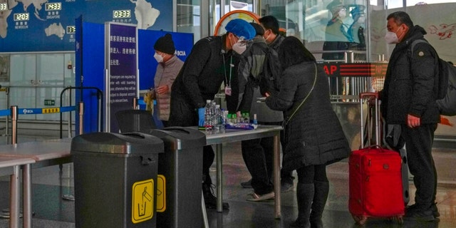 Passengers wearing face masks line up for security check before entering an international departure gate at the Beijing Capital International Airport in Beijing, Thursday, Dec. 29, 2022. 