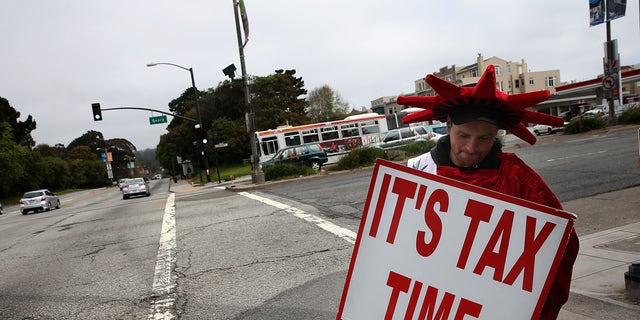 SAN FRANCISCO, CA - APRIL 14: Aaron Lee holds a sign advertising income tax services for Liberty Tax Service on April 14, 2014 in San Francisco, California.  Tax preparers are helping last minute tax filers ahead of the April 15th deadline to file state and federal income taxes. The Internal Revenue Service is expecting an estimated 35 million returns in the week leading up to the deadline. 