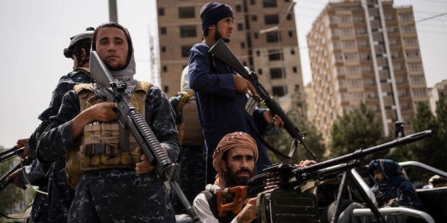 Taliban fighters escort women march in support of the Taliban government outside Kabul University, Afghanistan. 