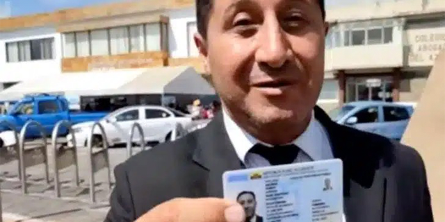 René Salinas Ramos holds up his ID. 