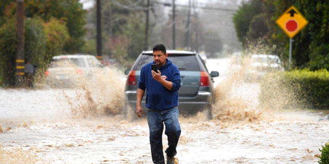 A resident walks along College Road after the area was flooded during a recent storm in Watsonville, Calif., on Monday, Jan. 9, 2023. 