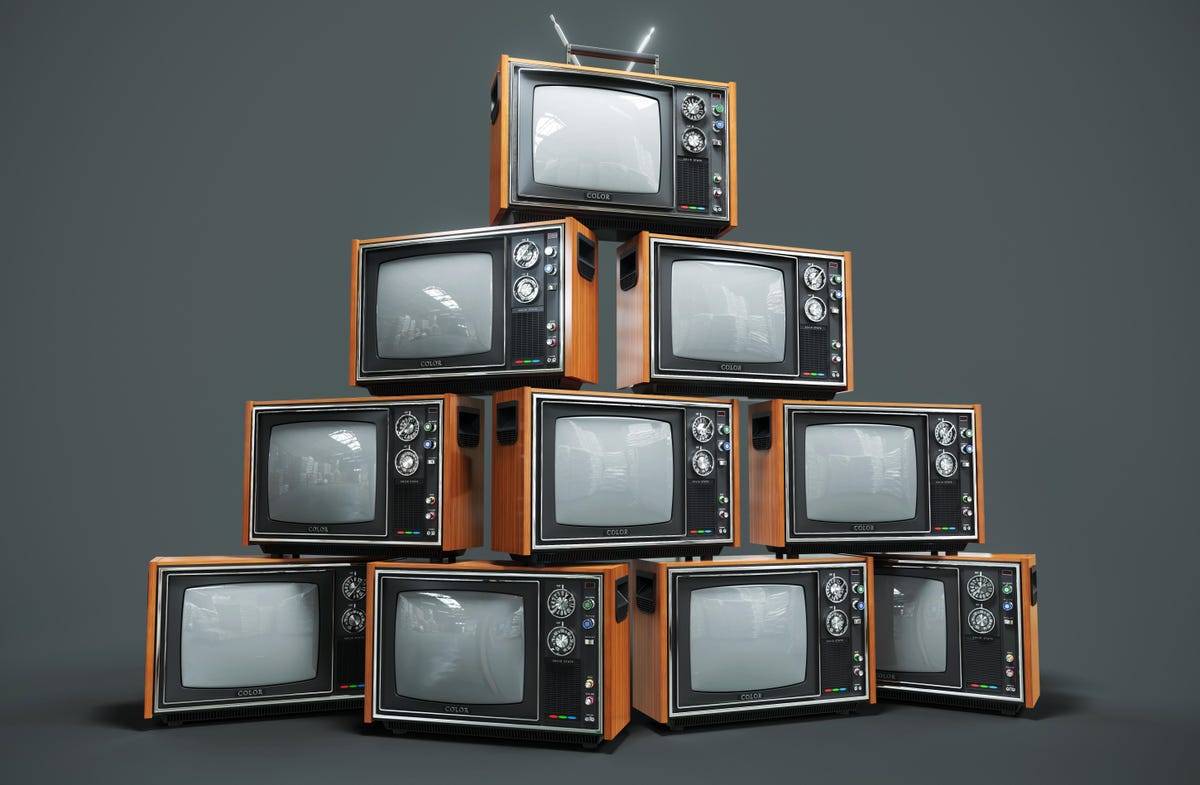 A pyramid of old tube-style CRT televisions on a flat gray background.