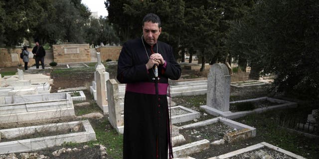 Hosam Naoum, a Palestinian Anglican bishop, pauses where vandals desecrated more than 30 graves at a historic Protestant Cemetery on Jerusalem's Mount Zion in Jerusalem, Wednesday, Jan. 4, 2023.