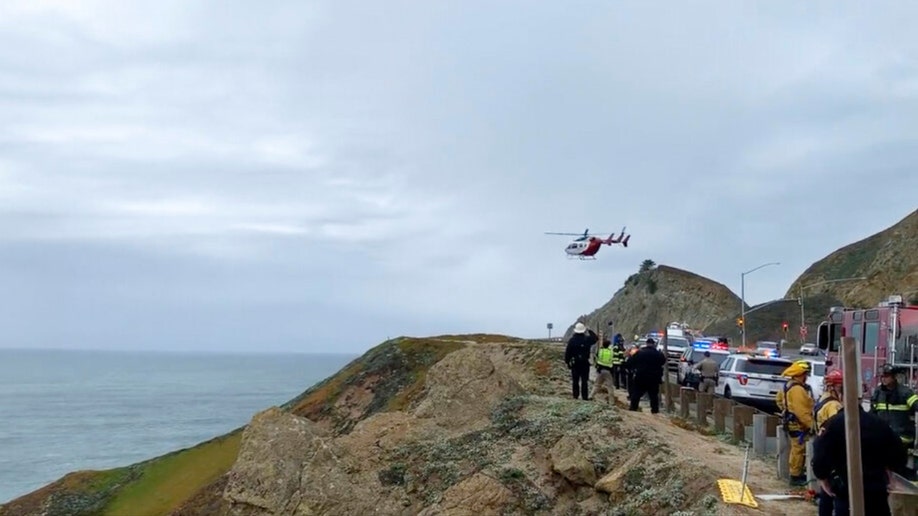 Emergency personnel respond to the scene after a Tesla plunged off a cliff along the Pacific Coast Highway