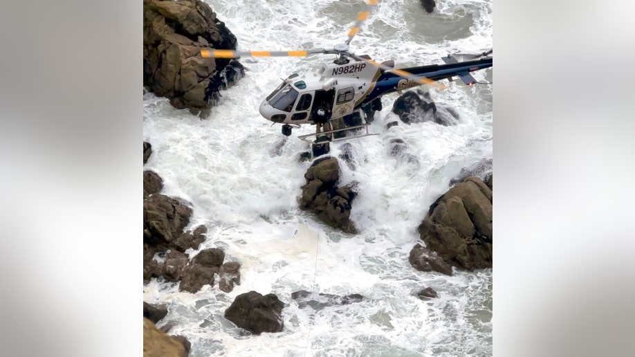 A helicopter works above choppy waters to rescue two adults and two young children who plunged off a northern California cliff