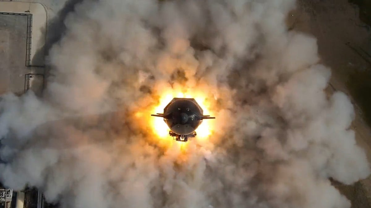Top-down view of SpaceX Starship single-engine static fire test shows the nose of Starship surrounded by fiery blaze and billows of smoke.