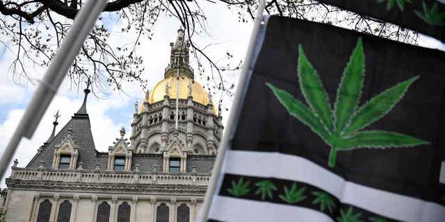 Flags with a marijuana leaf wave outside the Connecticut State Capitol building, on April 20, 2021, in Hartford, Connecticut. The state's first round of retail cannabis sales for adults 21 and older was set to begin on Jan. 10, 2023, at seven existing medical marijuana establishments across the state.