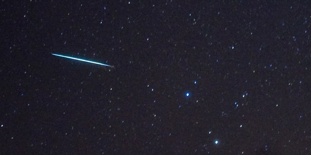 A meteor (L) from the Geminids meteor shower enters the Earth's atmosphere past the stars Castor and Pollux (two bright stars, R) on December 12, 2009 above Southold, New York.