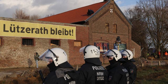 Riot police stand outside a farmhouse in which activists barricaded themselves at the settlement of Luetzerath in Germany.